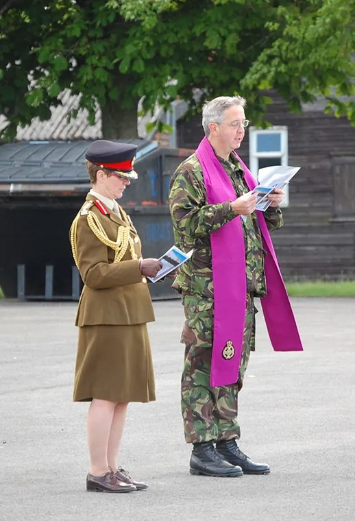 A chaplain reads, beside an officer